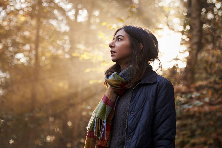 Femme dans les bois respirant l'air frais avec le soleil durant l'hiver