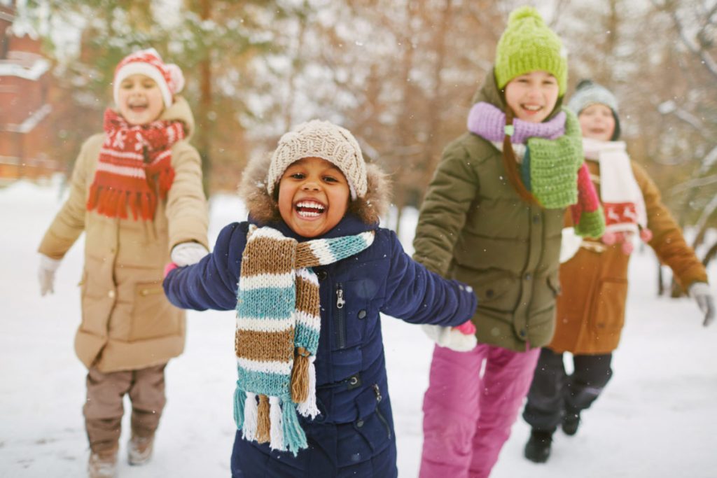 4 jeunes enfants main dans la main s'amusant dans la neige