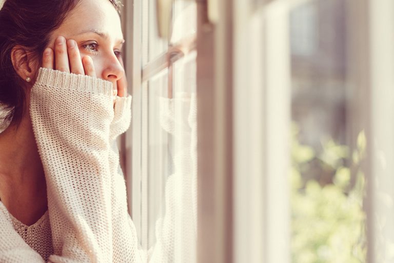 Jeune femme déprimée regardant par la fenêtre