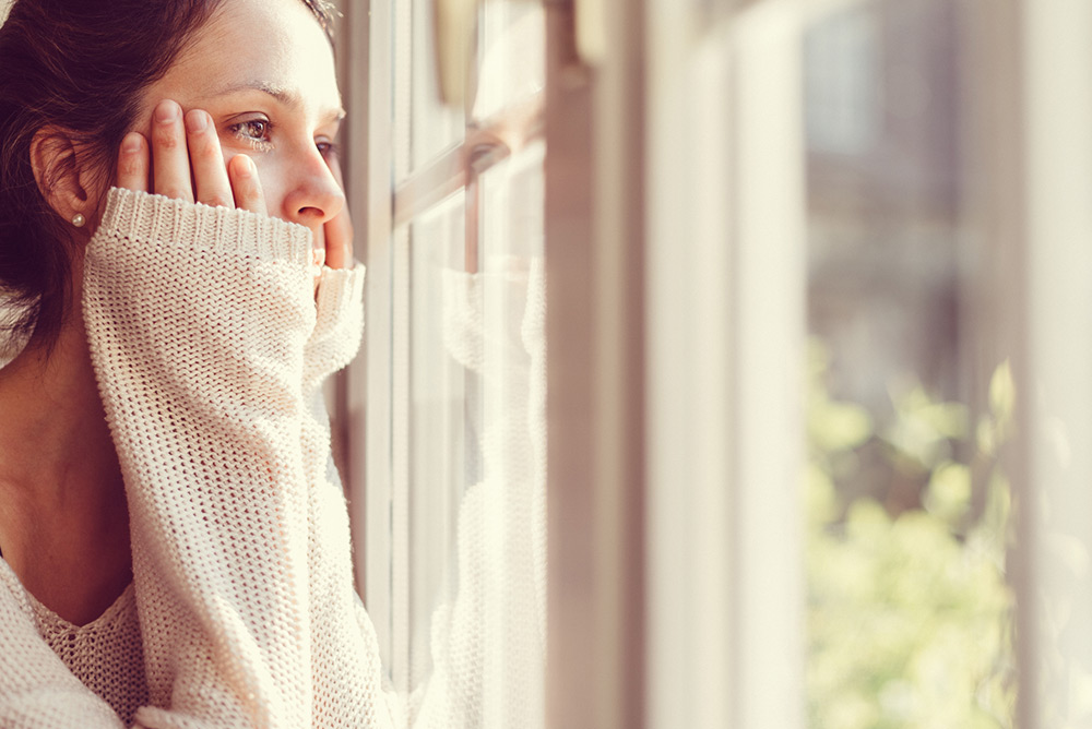 Jeune femme déprimée regardant par la fenêtre