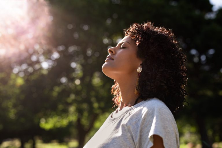 Jeune femme ressentant l'air et le soleil sur son visage