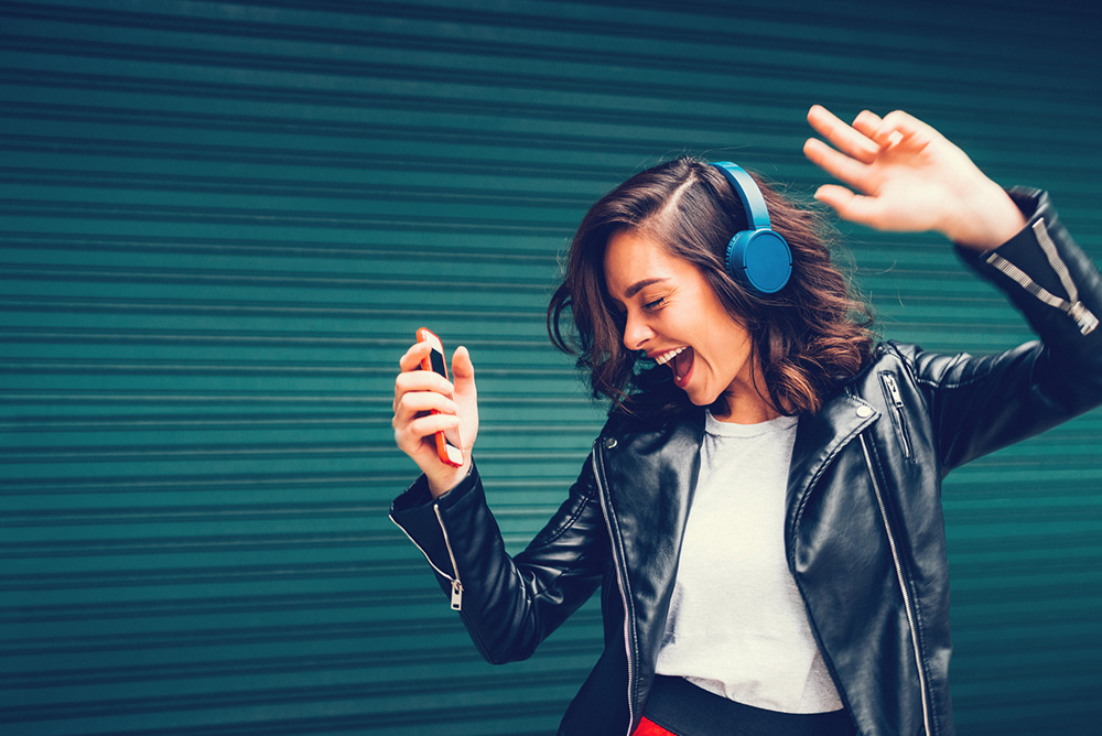 Jeune femme écoutant de la musique avec casque heureuse et énergique