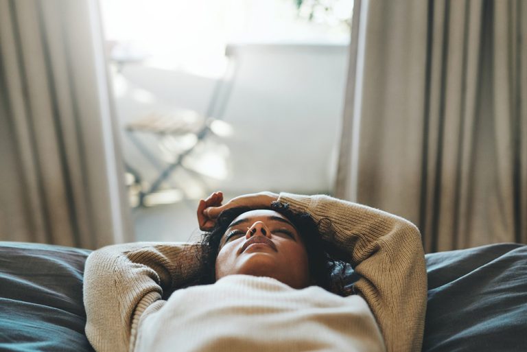 Jeune femme fatiguée qui ferme les yeux allongée sur le canapé