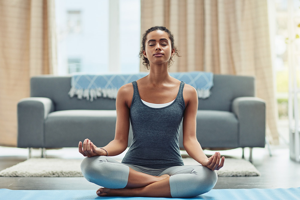 Jeune femme dans le salon pendant séance de yoga en position du lotus