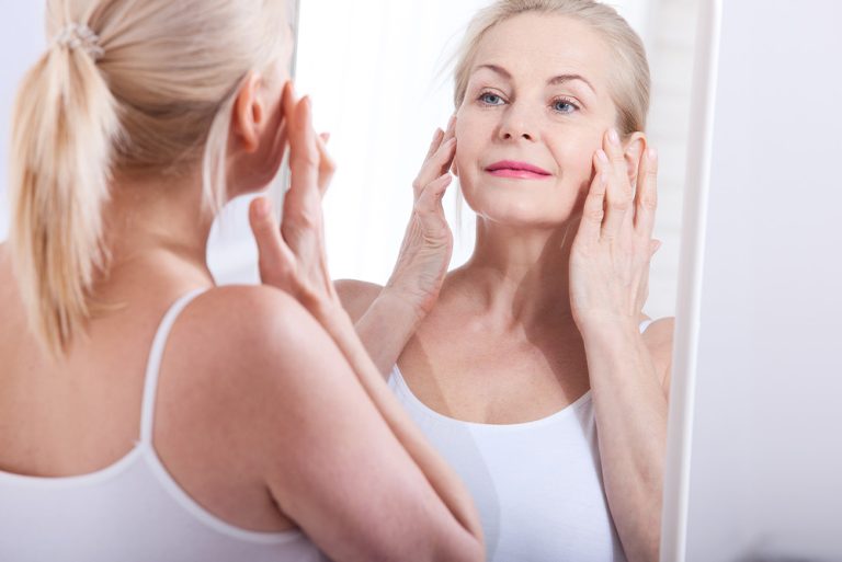 Femme observant sa peau dans un miroir
