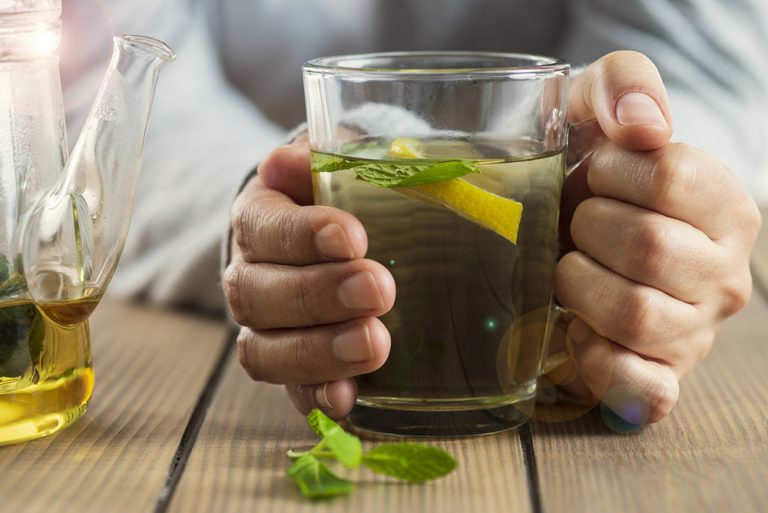 Plan rapproché sur verre de tisane avec des plantes et citron - phytothérapie