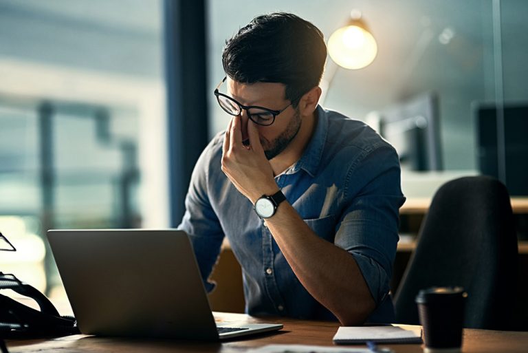 Jeune homme qui travaille devant son ordinateur fatigué et stressé