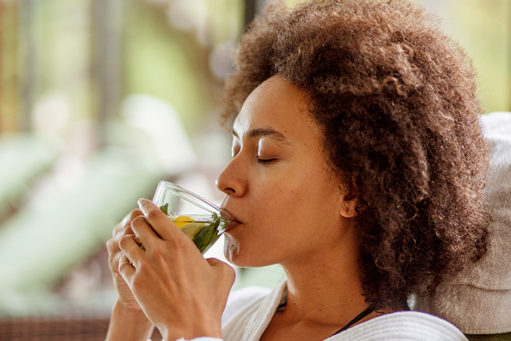 Femme avec les yeux fermés dégustant une tisane paisiblement