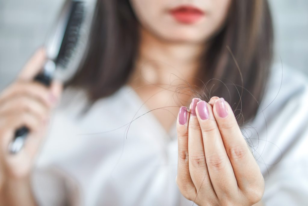 gros plan d'une femme tenant des cheveux de la brosse à cheveux