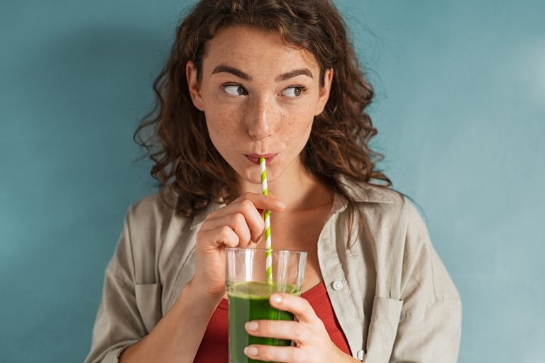 Jeune femme buvant un jus detox à la paille