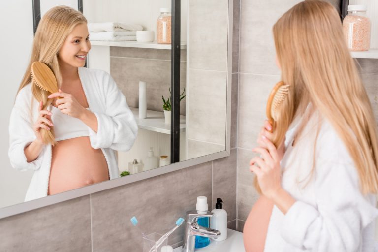 Femme enceinte se brossant les cheveux dans le mirroir