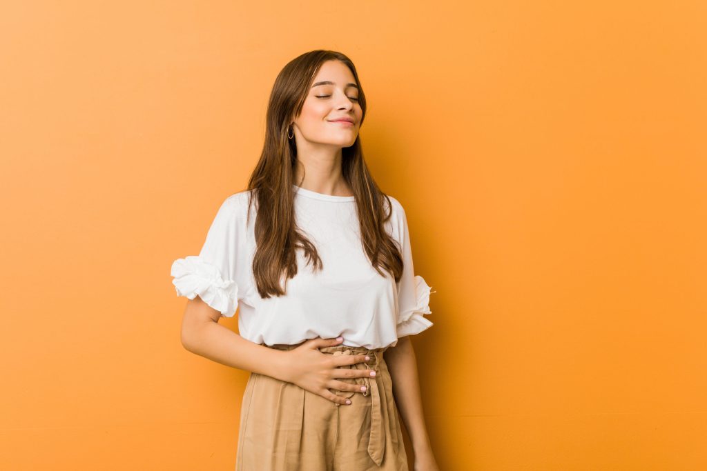 Jeune femme se touchant le ventre et souriant